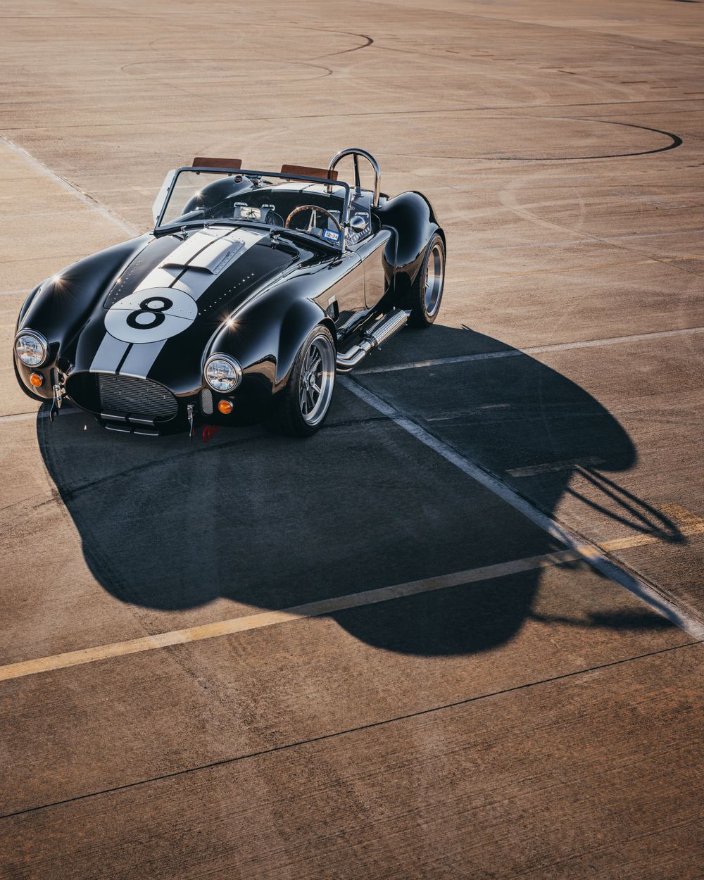 Classic black vintage racing car photographed from multiple angles on a wooden floor.