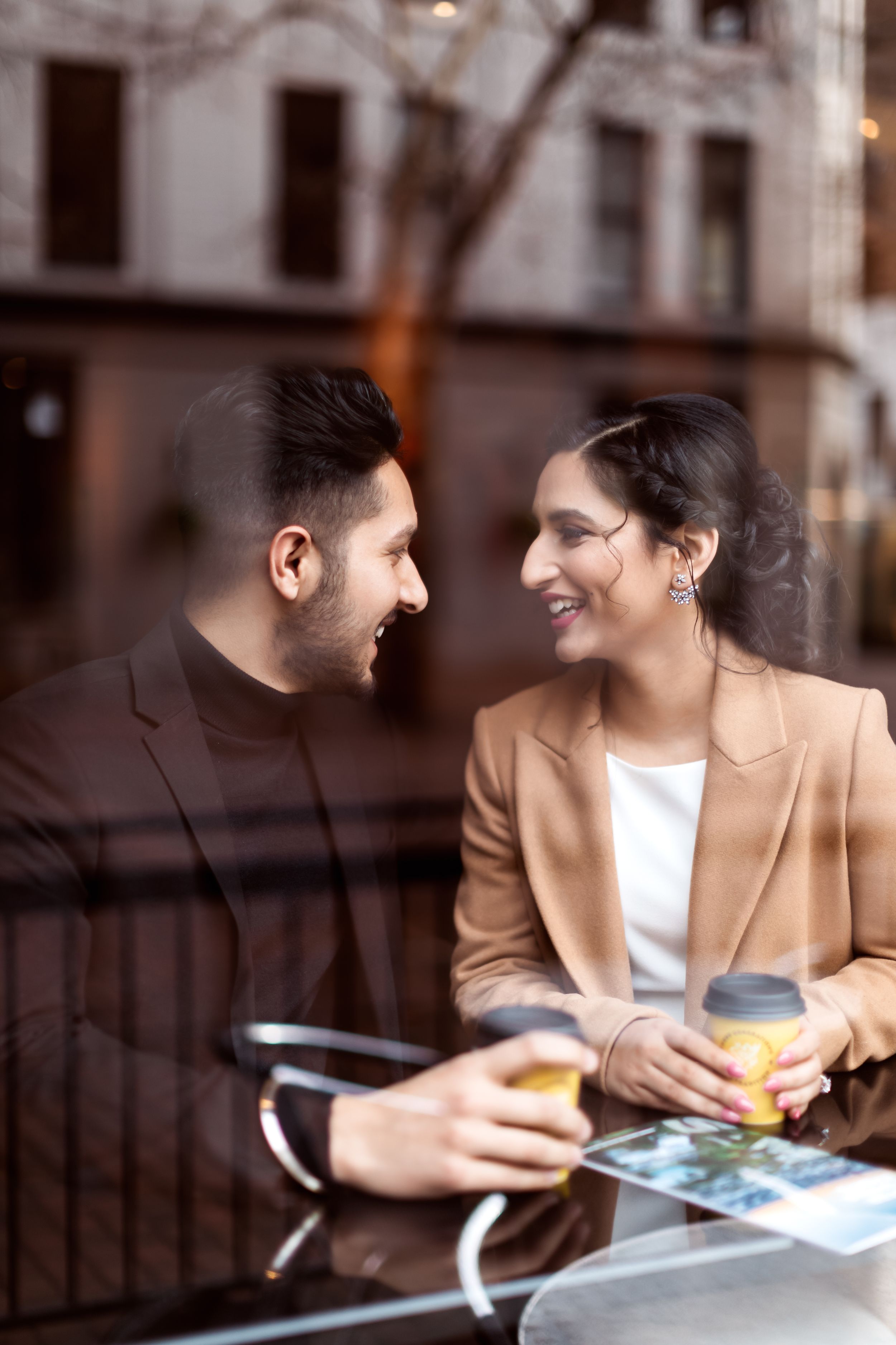 A couple enjoys drinks and conversation at an outdoor cafe table.