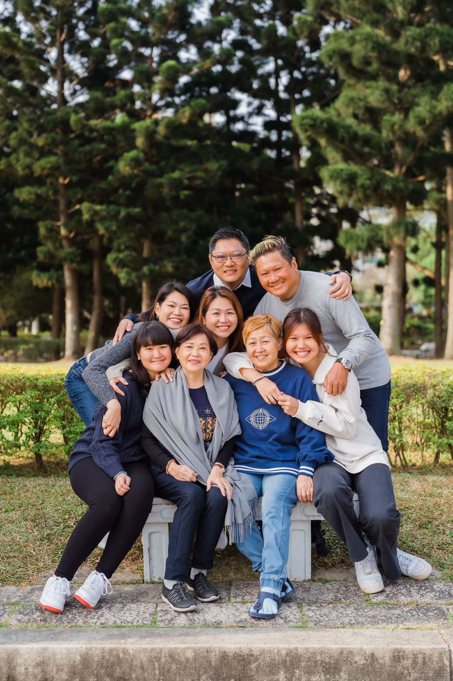 Group enjoying playful outdoor gathering on concrete bench in park setting.