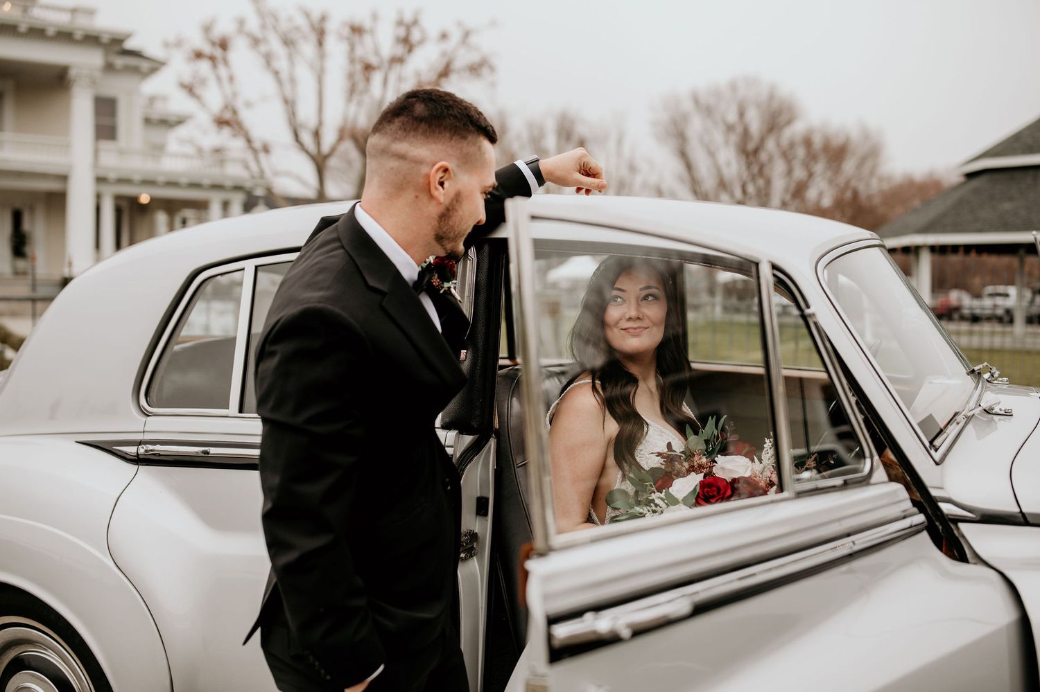 Groom stares at his bride as she sits in the vintage Rolls Royce.