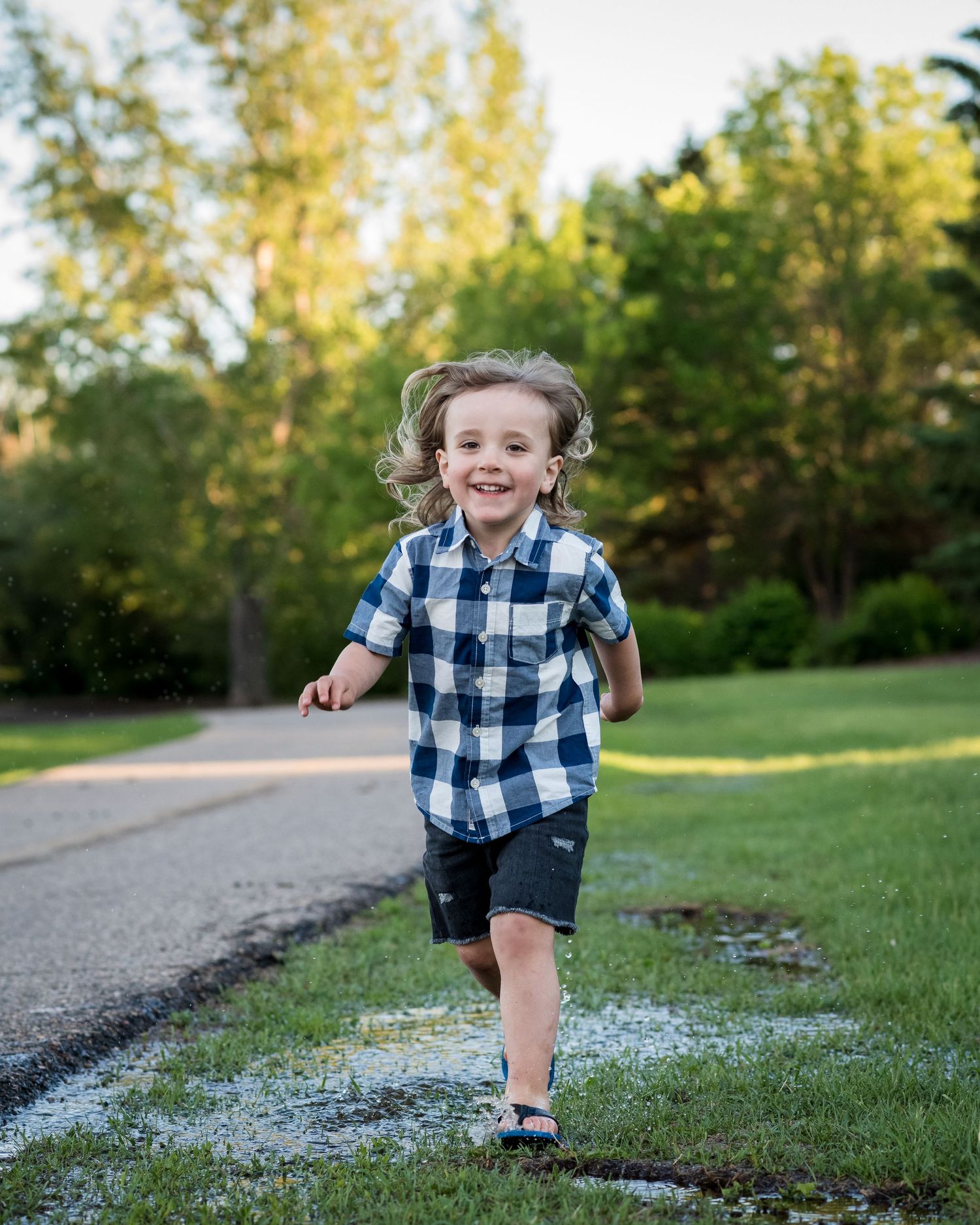 Child running outdoors wearing navy plaid shirt and shorts.