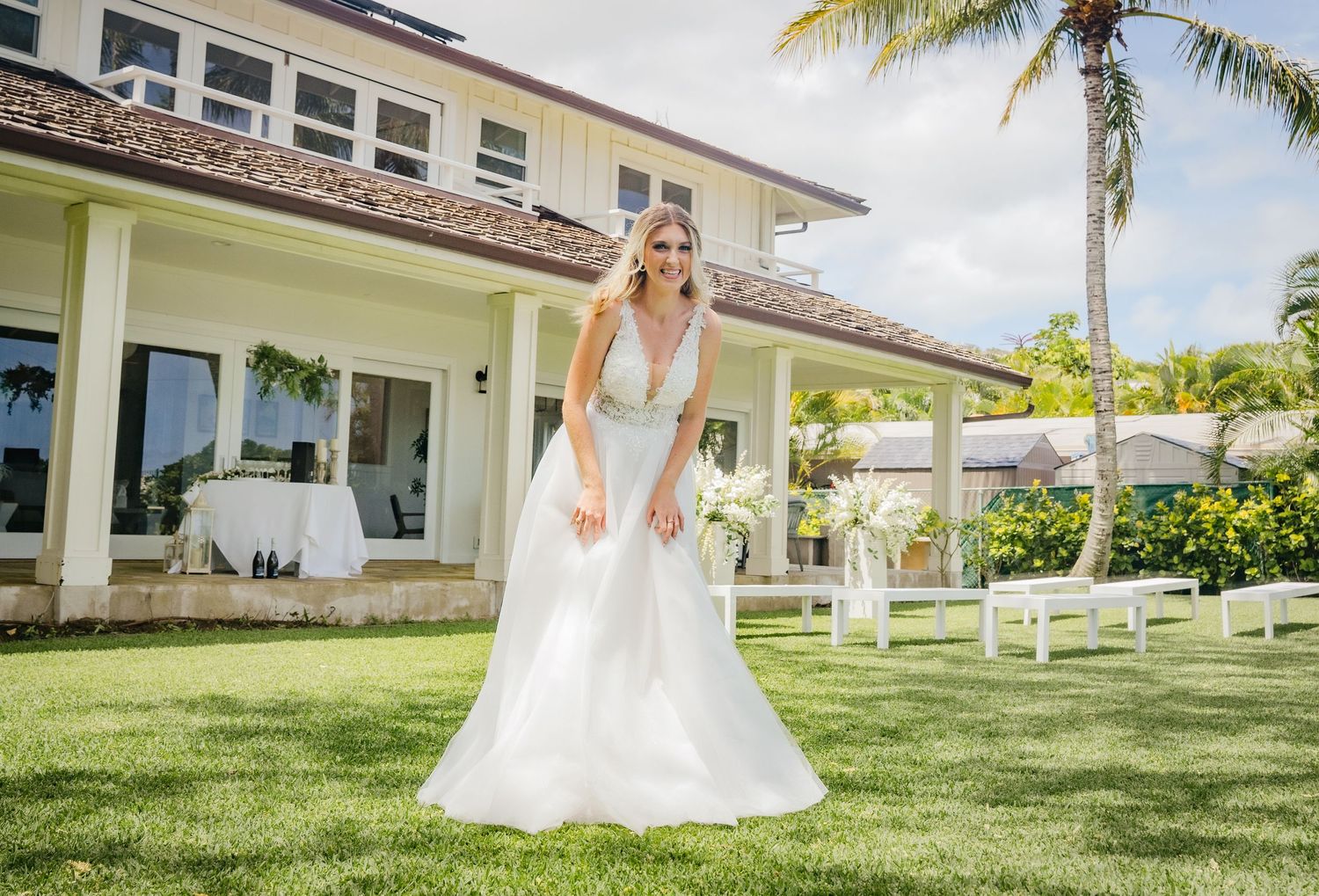 A stunning wedding scene with a flowing white gown on a tropical lawn with palm trees and ocean views.