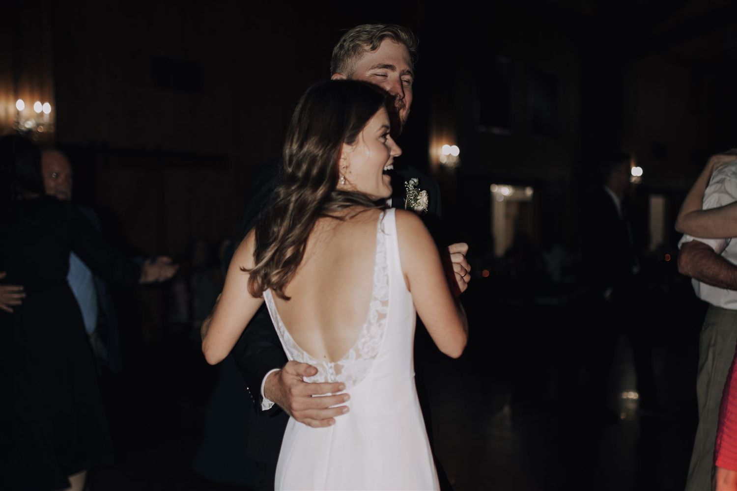 Couple sharing an intimate slow dance at an indoor wedding reception with dimly lit ambiance.