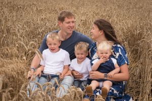 A family portrait with three children, all having a cuddle in a wheat field.
