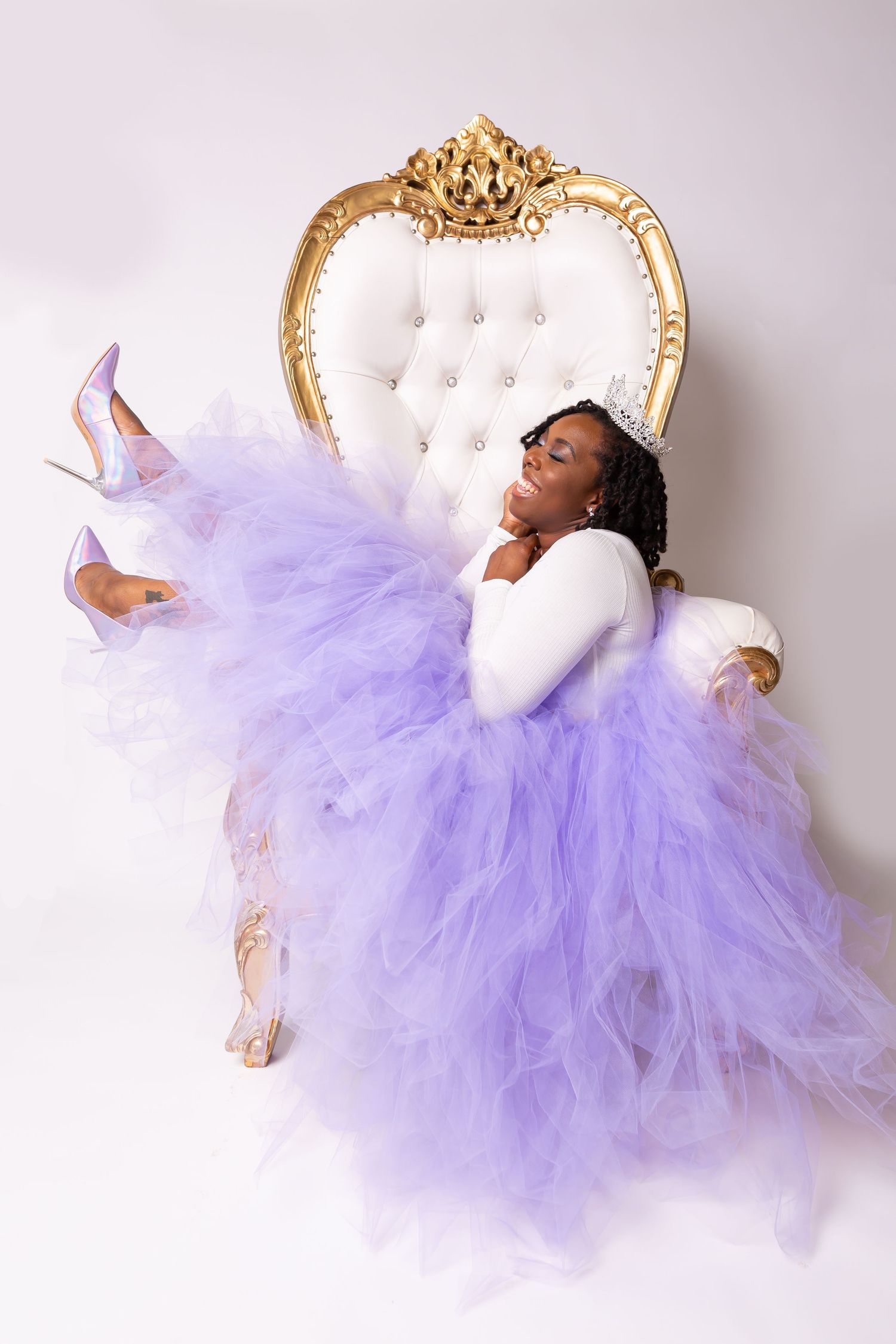 Dramatic reclining pose in lavender tulle gown on elegant white and gold throne chair.