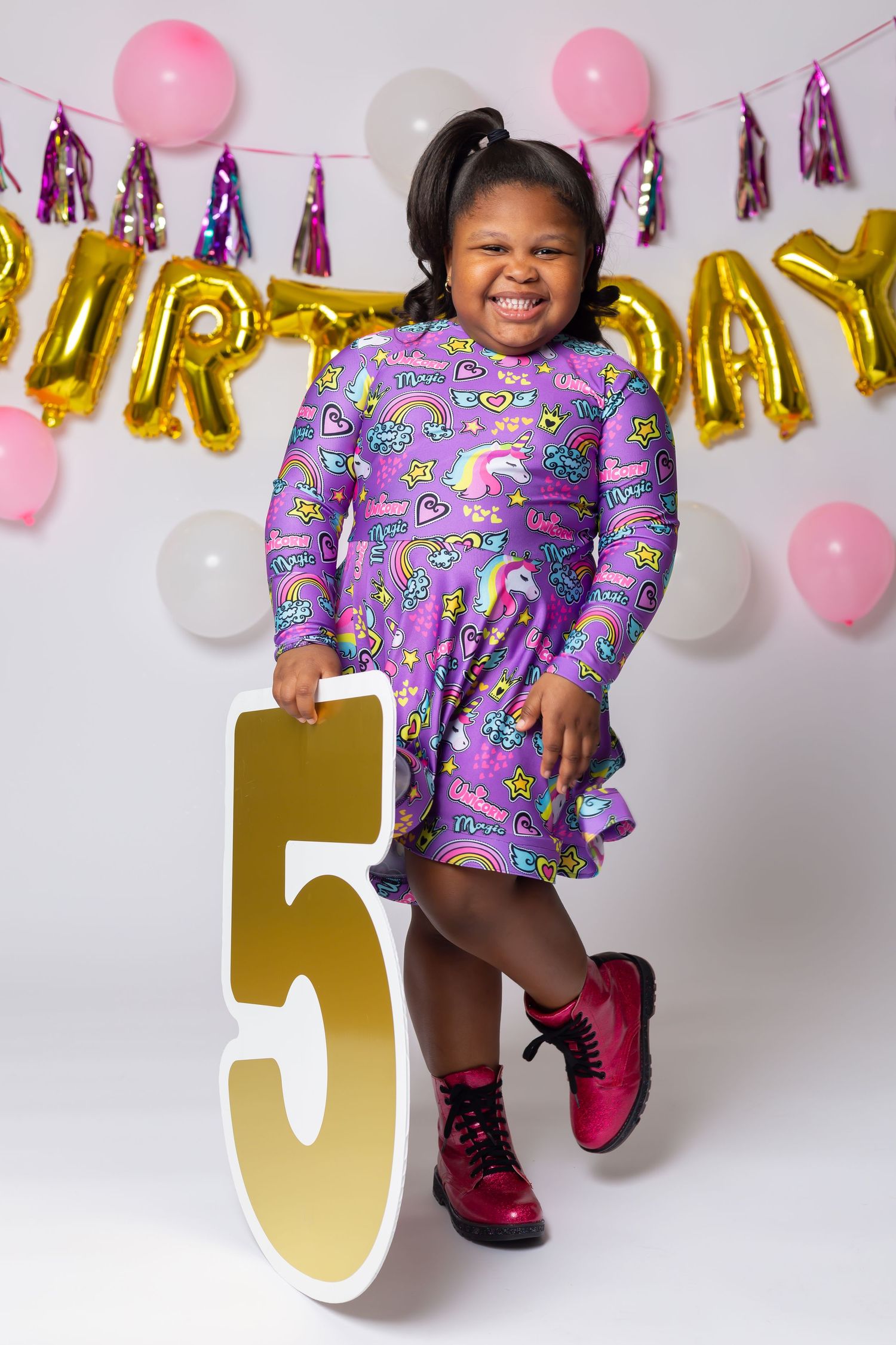 Birthday celebration with gold number 5, pink balloons, and purple patterned dress.