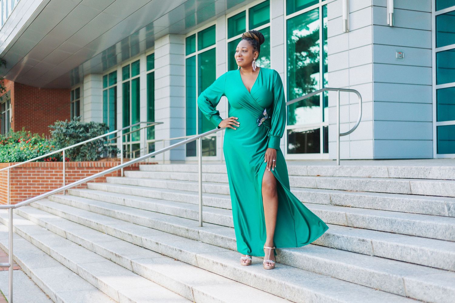 Elegant pose in flowing green formal dress on stone steps.