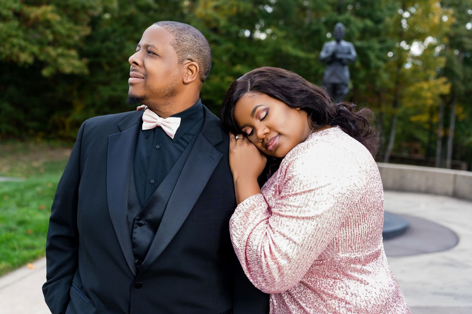 A tender moment shared between a couple in formal attire against an autumn outdoor setting.