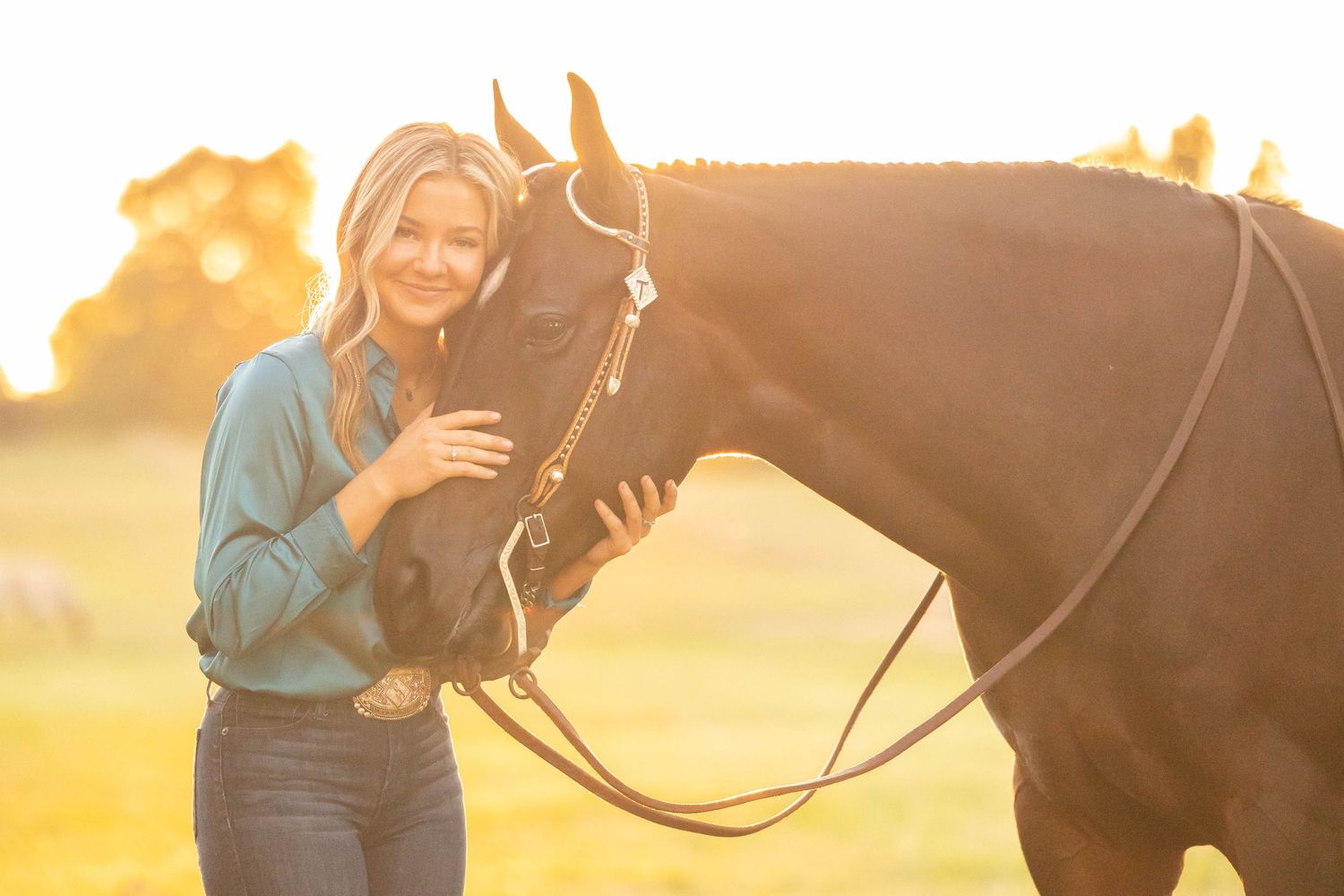 Girl in green silk blouse standing with her bay mare in a western bridle