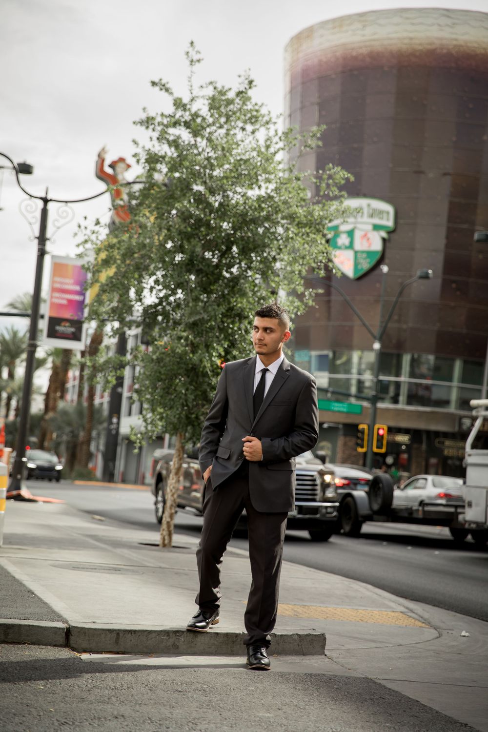 Urban portrait of person in black suit walking confidently on city street.