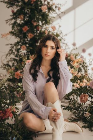 Elegant boudoir portrait with roses and soft window lighting.