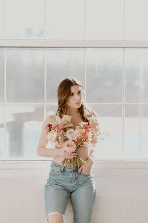 Artistic portrait with soft pink roses and vintage window lighting.