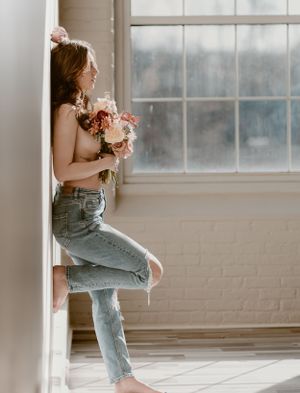 Dreamy portrait with pink roses against bright window backdrop.