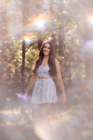 Ethereal portrait with bokeh effects and soft golden lighting in wooded setting.