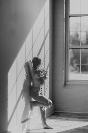 Black and white artistic portrait with dramatic window lighting.