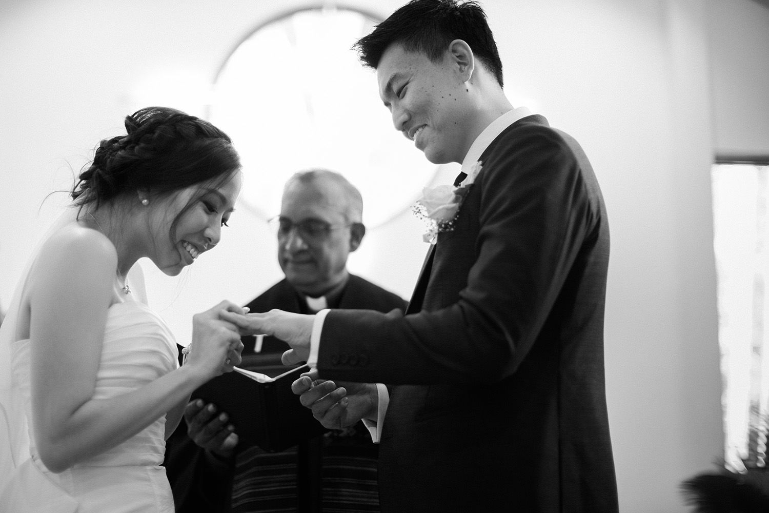 Bride putting ring onto her husband's finger in church