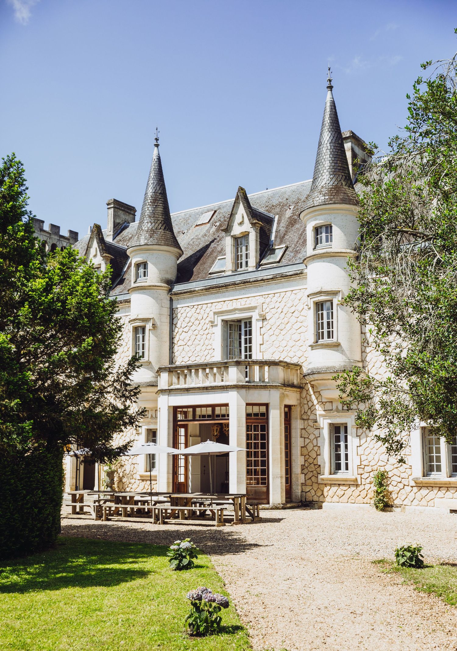 Majestic French chateau with turrets and stone exterior surrounded by manicured grounds.