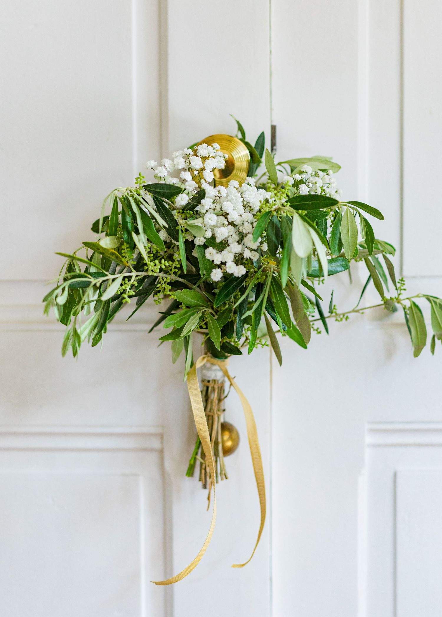A simple green and white wedding bouquet with trailing yellow ribbon.