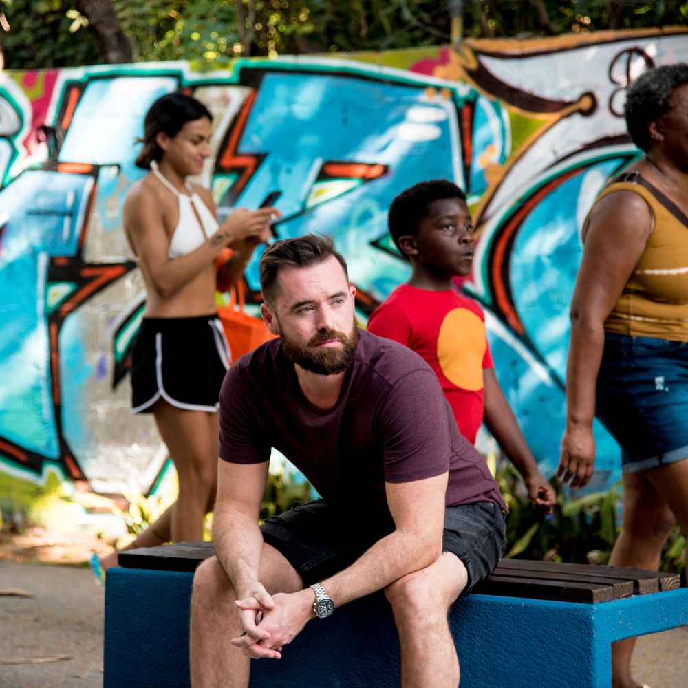 Ben sitting by Quinta Avenida with people passing behind him