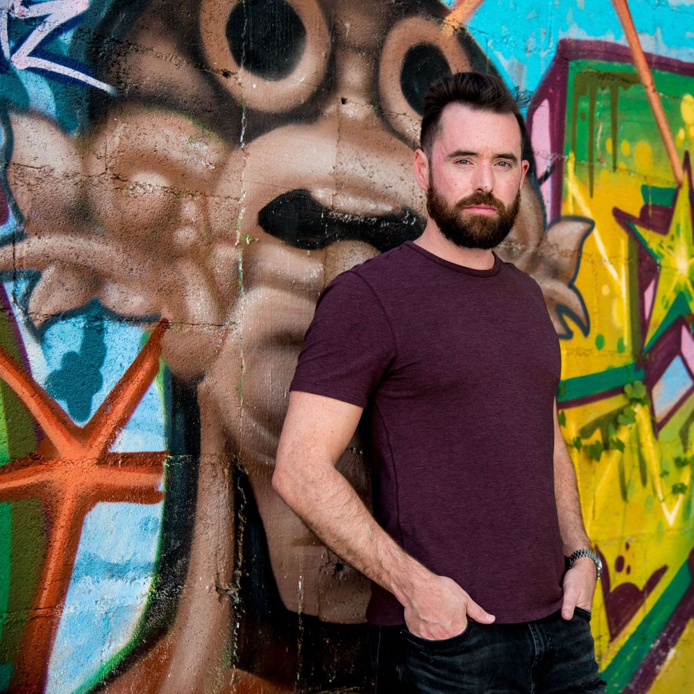 Ben standing in front of a colorful mural showcasing the street art of Playa del Carmen