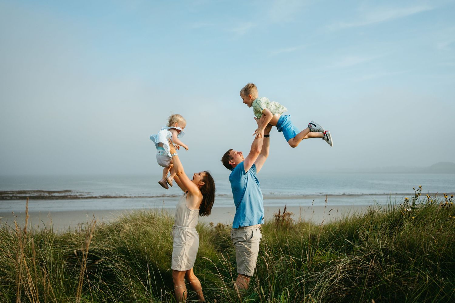 Playful scene at the beach with tall grass and ocean waves in the background.