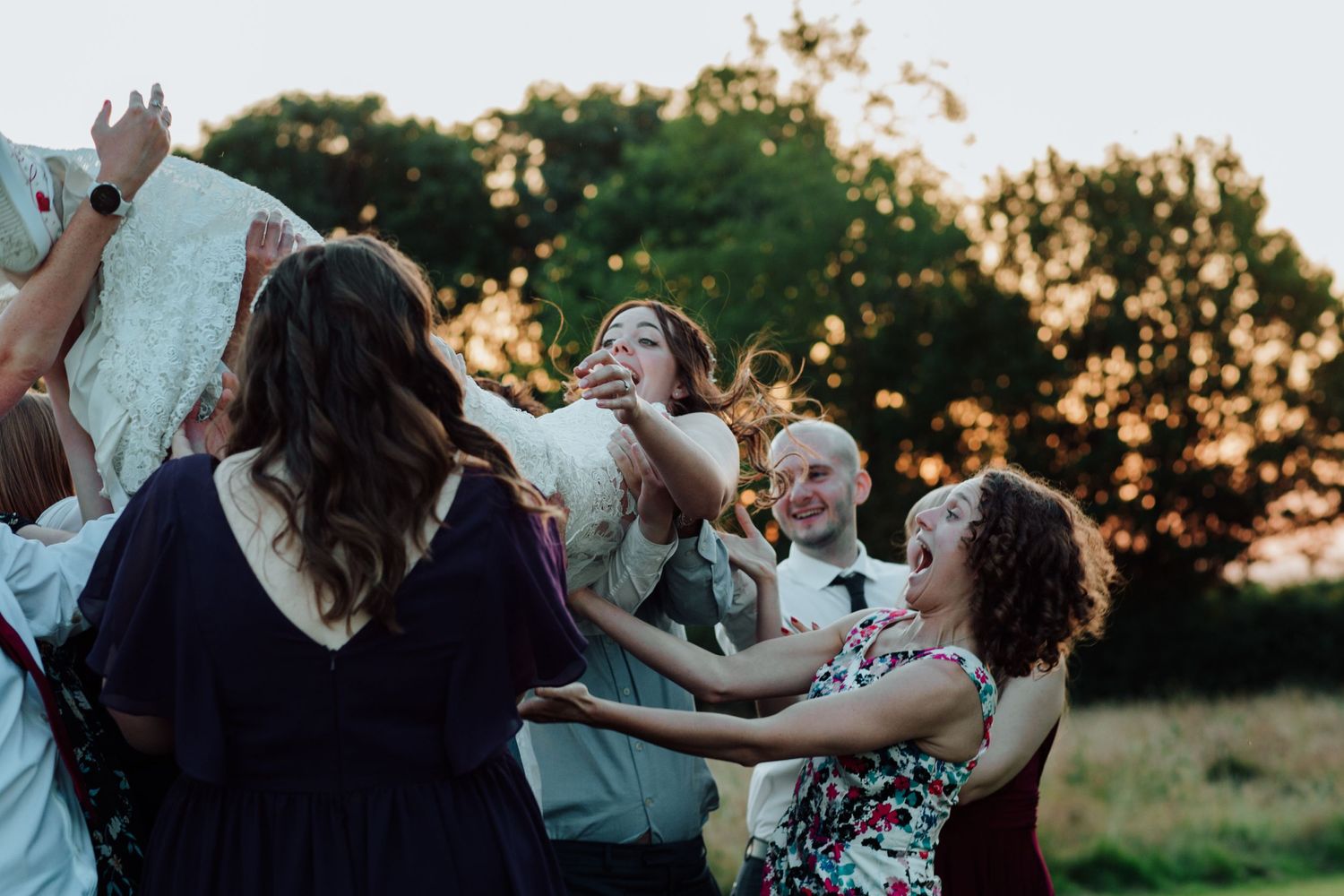 A joyous group dances together at sunset during a celebration outdoors.