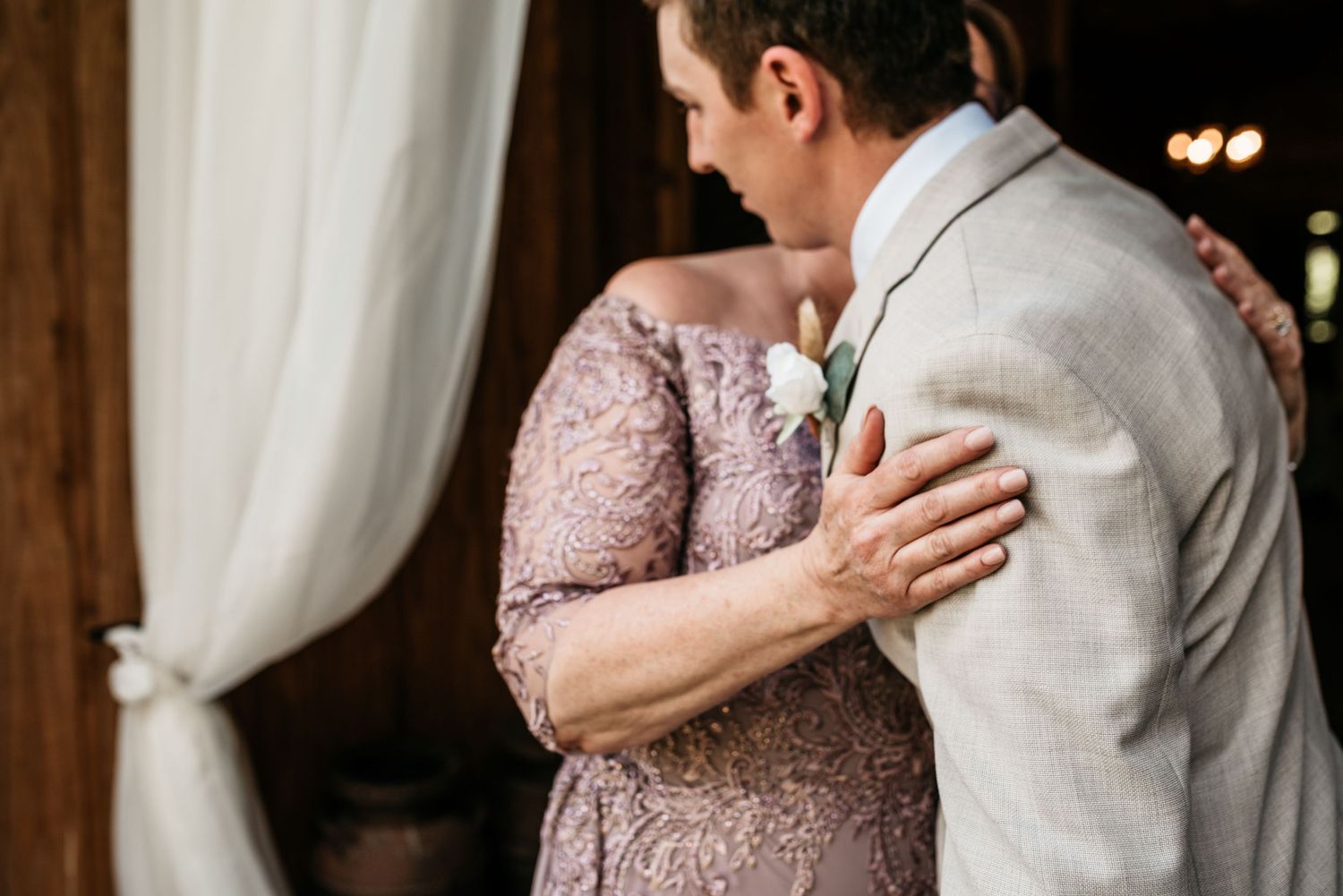 Close-up of emotional pre-wedding boutonniere pinning moment in formal wear.