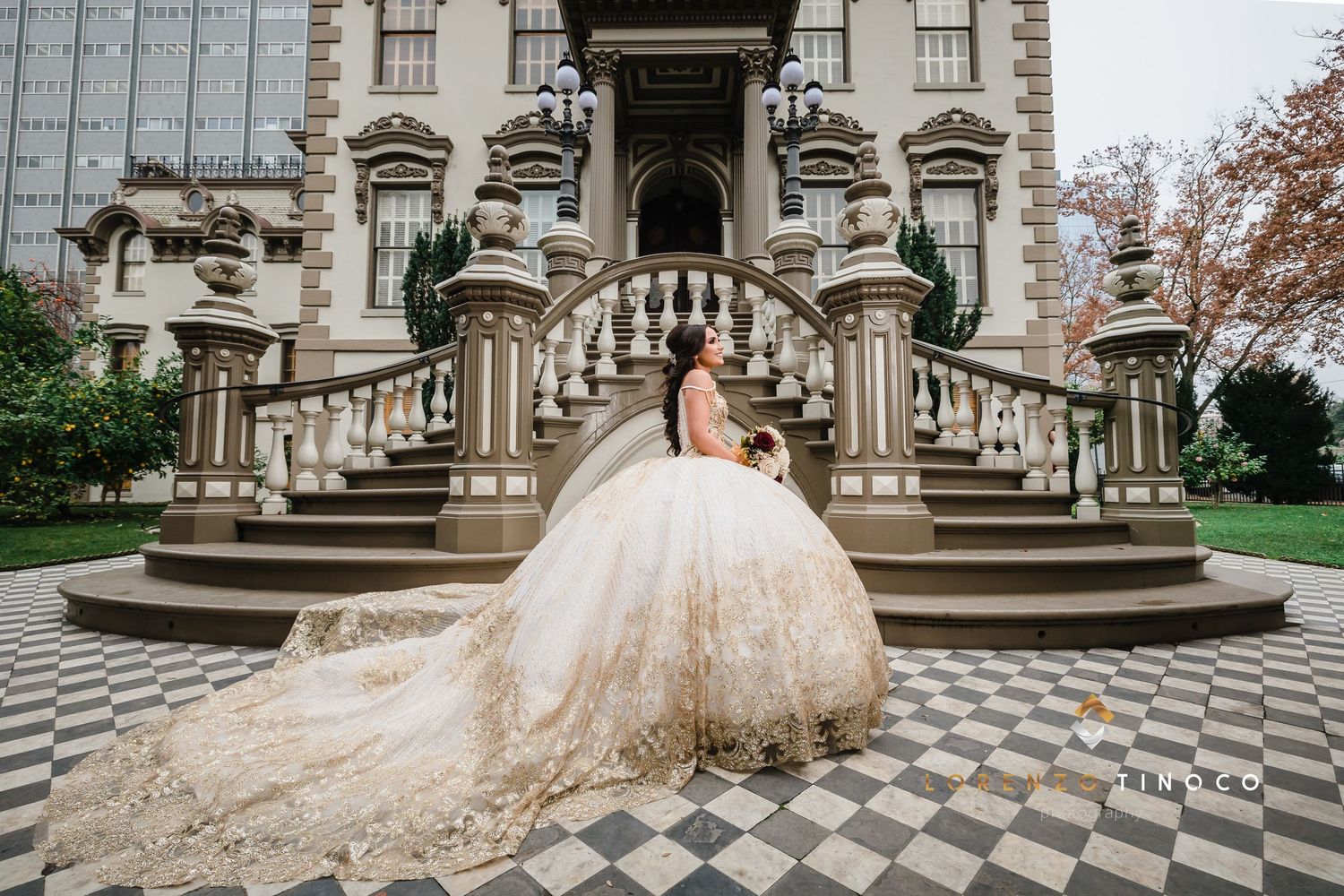 An elegant bridal portrait on ornate stone steps with a flowing champagne-colored ballgown.