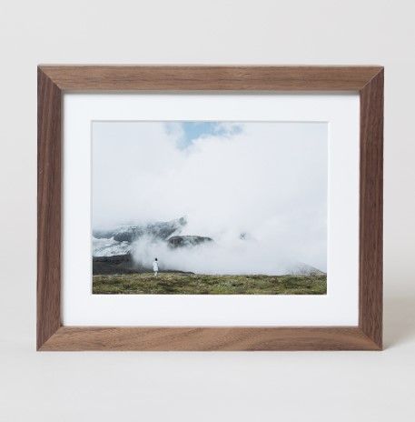 Landscape photograph of misty mountains in a wooden frame against white background.