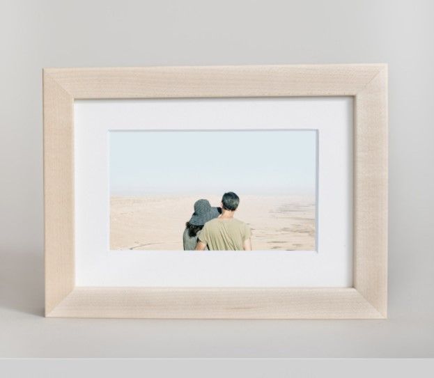 A framed desert landscape photograph in a light wooden frame.