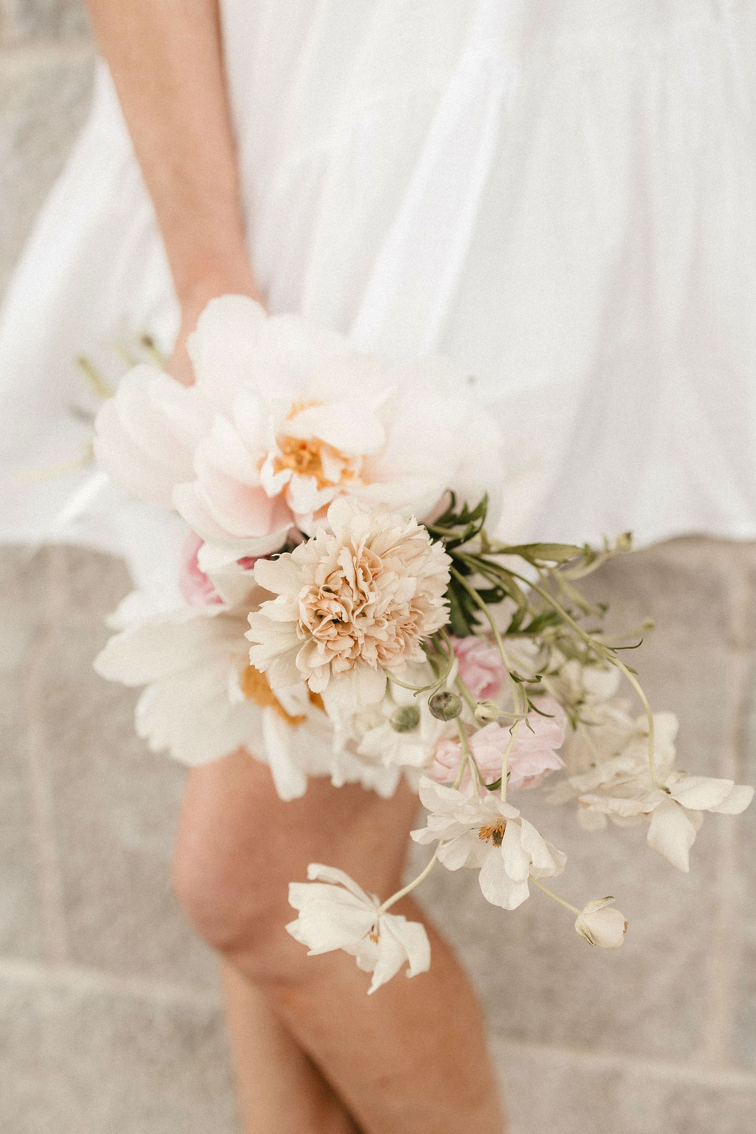 A delicate bridal bouquet featuring soft pink peonies and white floral accents.