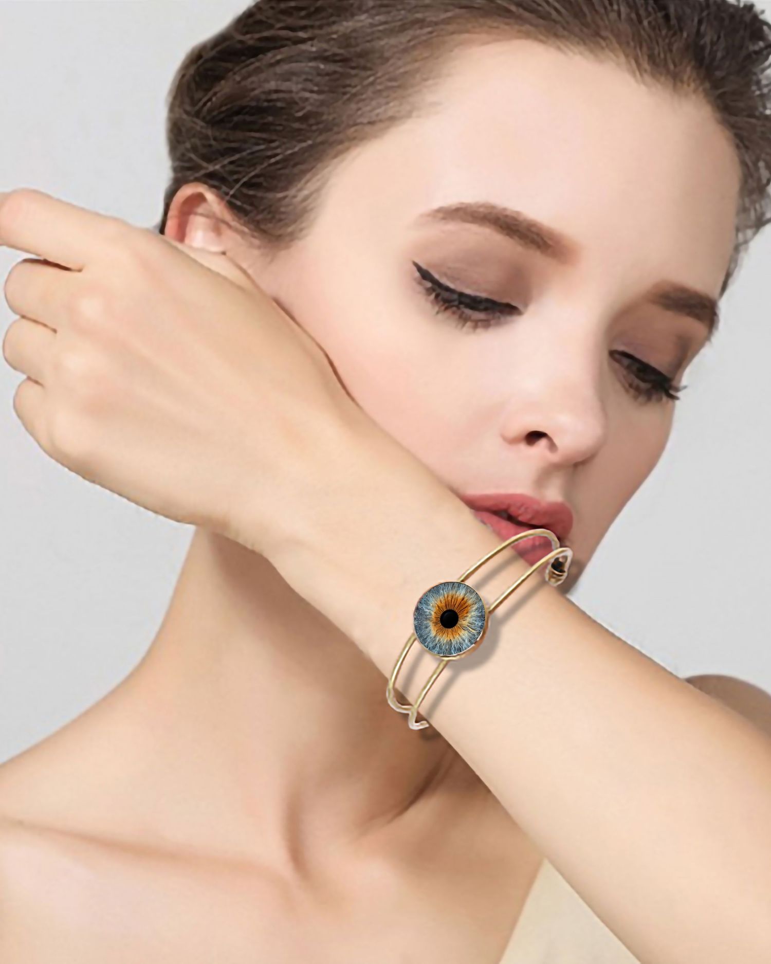Close up of a delicate gold bracelet featuring an iris design against pale skin.