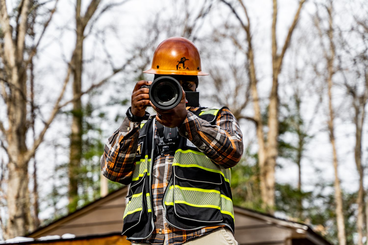 Construction worker in safety gear with professional camera equipment outdoors.