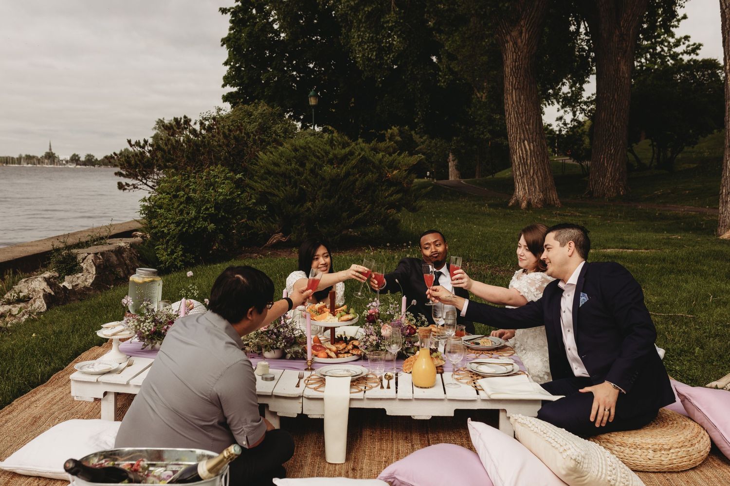 Friends enjoying an outdoor picnic feast by the waterfront at sunset.