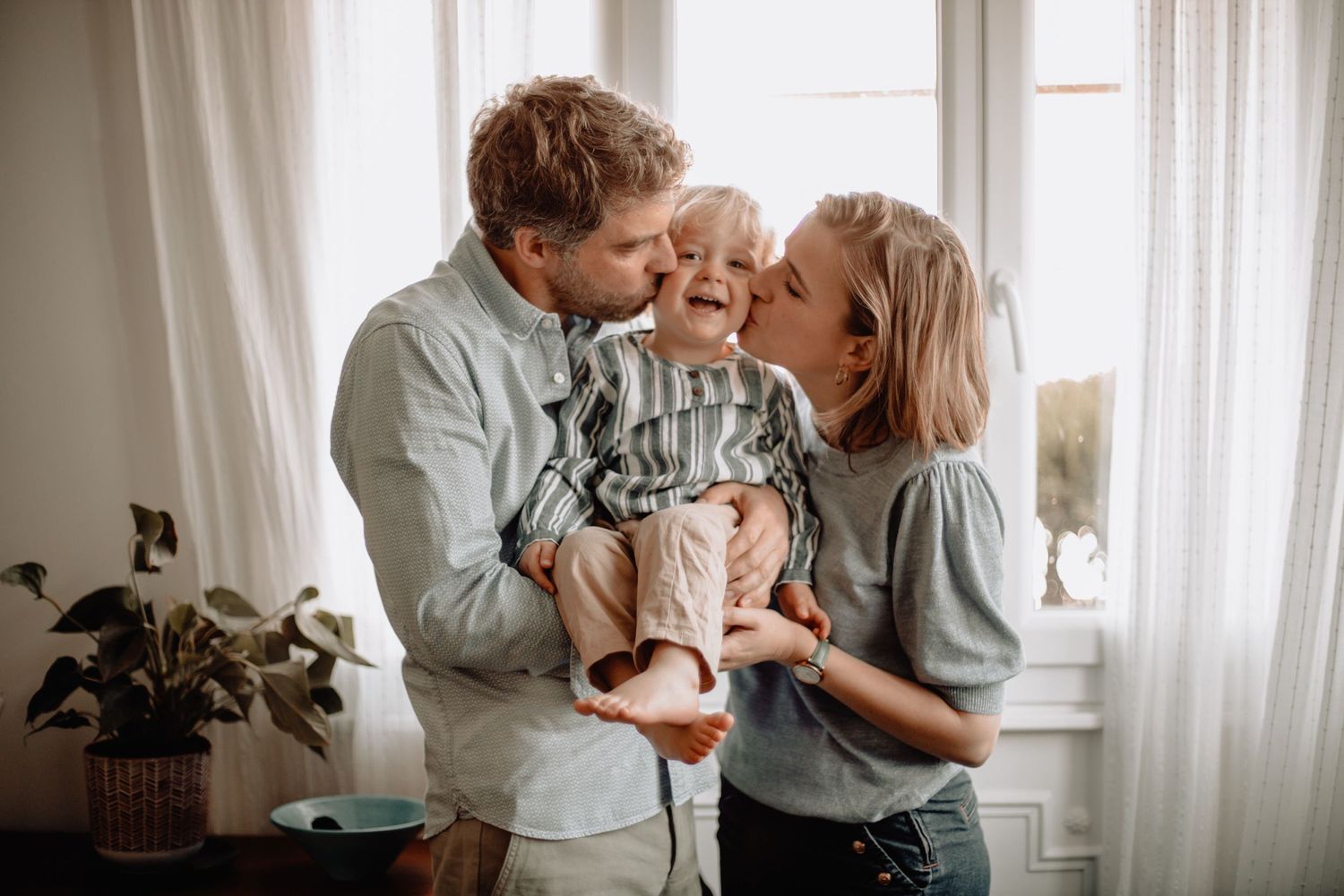 Séance photo famille en intérieur, rires et complicité capturés dans un cadre naturel.