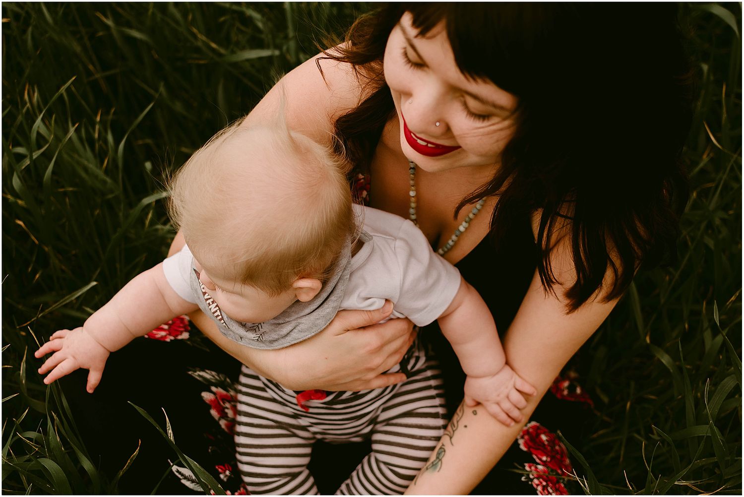 An intimate portrait of parental love as a baby in striped pants is held close in an outdoor setting.