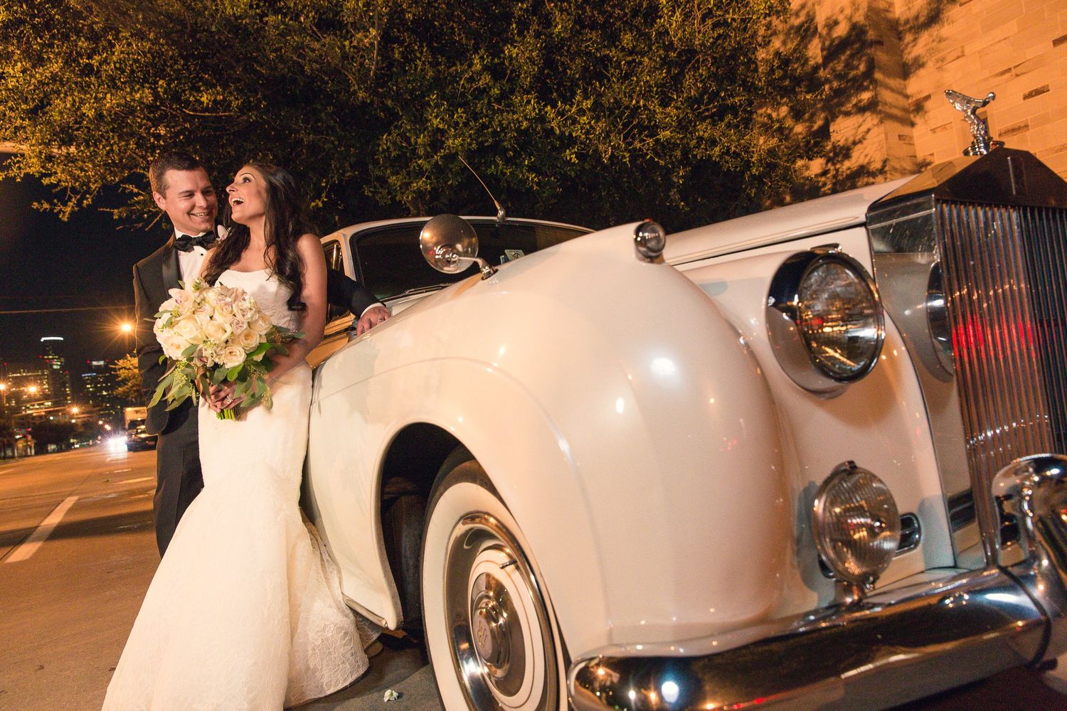 Elegant cream-colored vintage Rolls Royce parked at night during a wedding celebration.
