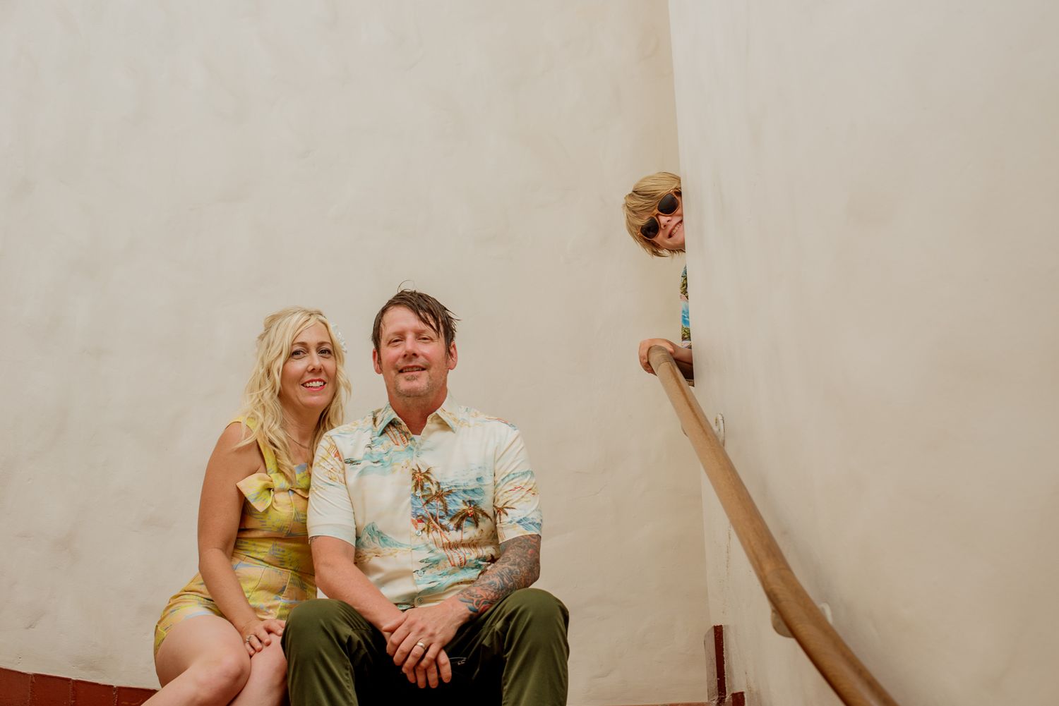 Family sitting in stairwell with son peeking around corner