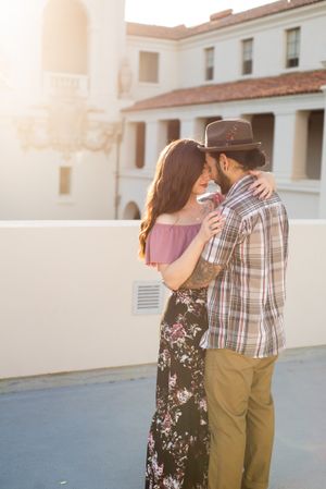 A romantic sunset moment between a couple on a rooftop with Mediterranean style architecture.