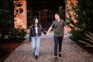 A couple walks hand in hand down a gravel path at sunset.