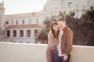 A couple shares a tender moment against Spanish colonial architecture during sunset.