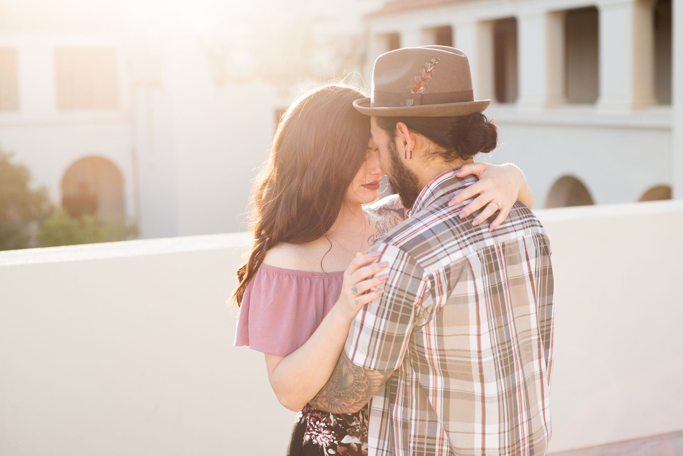 A tender moment captured between a couple against white architecture at sunset.