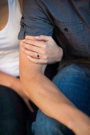 Close-up shot of hands with an engagement ring in natural lighting.