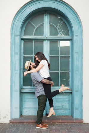 A couple shares intimate moments in front of a vintage turquoise arched doorway.