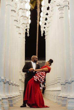 Romantic dance poses between columns in classical architecture setting.