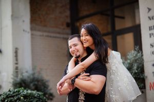 A joyful couple embraces outdoors near a brick building.
