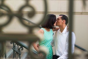 Two people share an intimate moment on outdoor steps with decorative shadows cast on the wall.