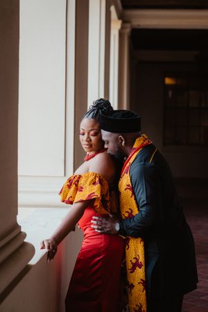 Intimate moment between couple in formal attire against arched hallway backdrop.