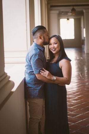 Engagement photo of couple in formal wear standing in elegant hallway.