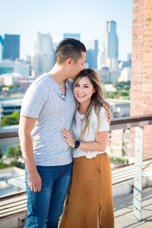 Happy couple embracing on rooftop terrace with downtown skyline in background.